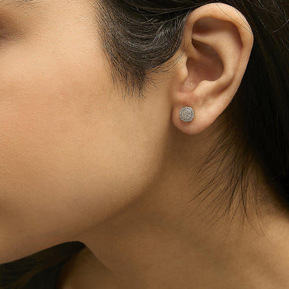 Close-up side view of a model wearing a pair of yellow metal round cluster earrings featuring white gemstones in prong settings.
