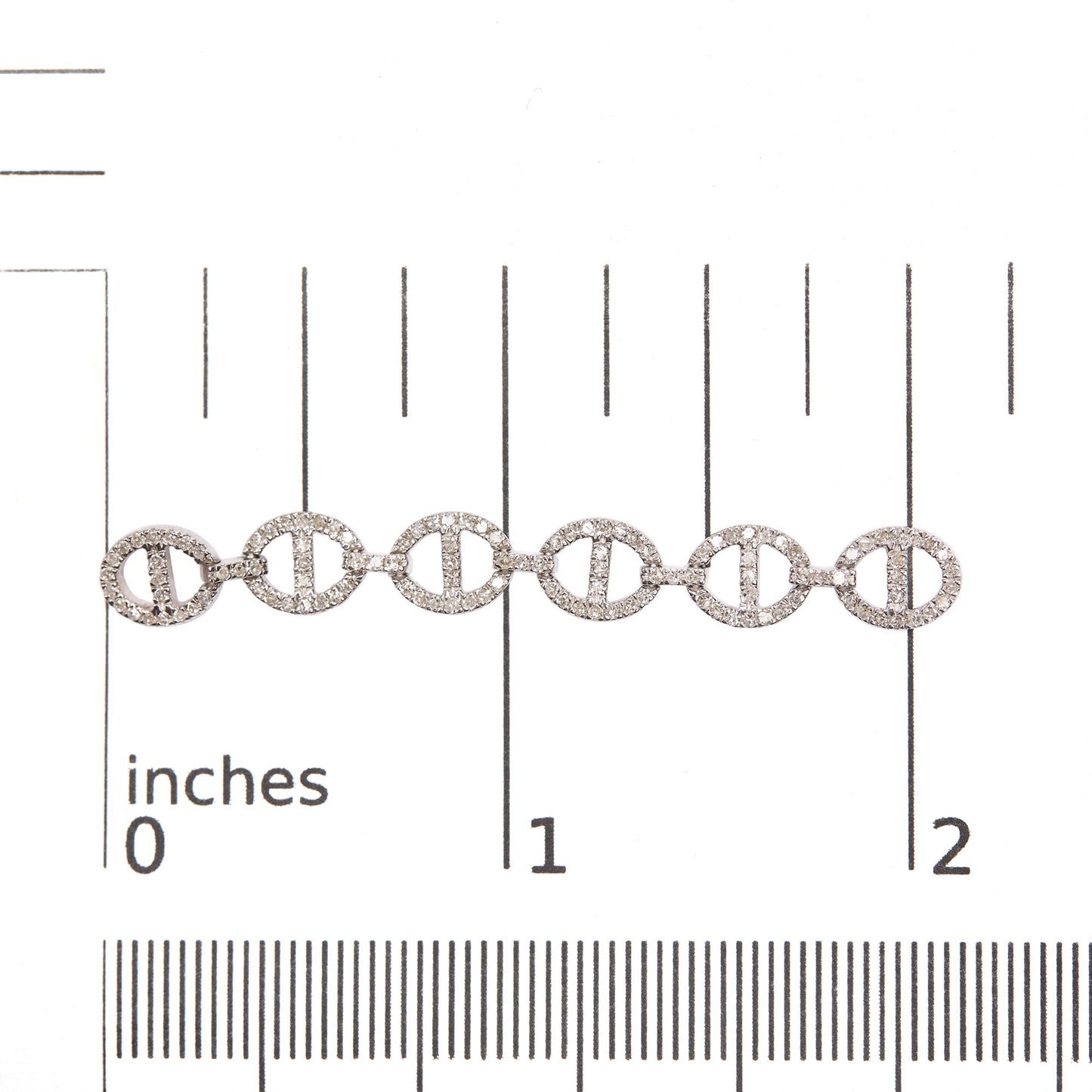 Close-up front angle of white earrings placed on a scale, featuring several linked oval shapes encrusted with round white gemstones in prong settings.