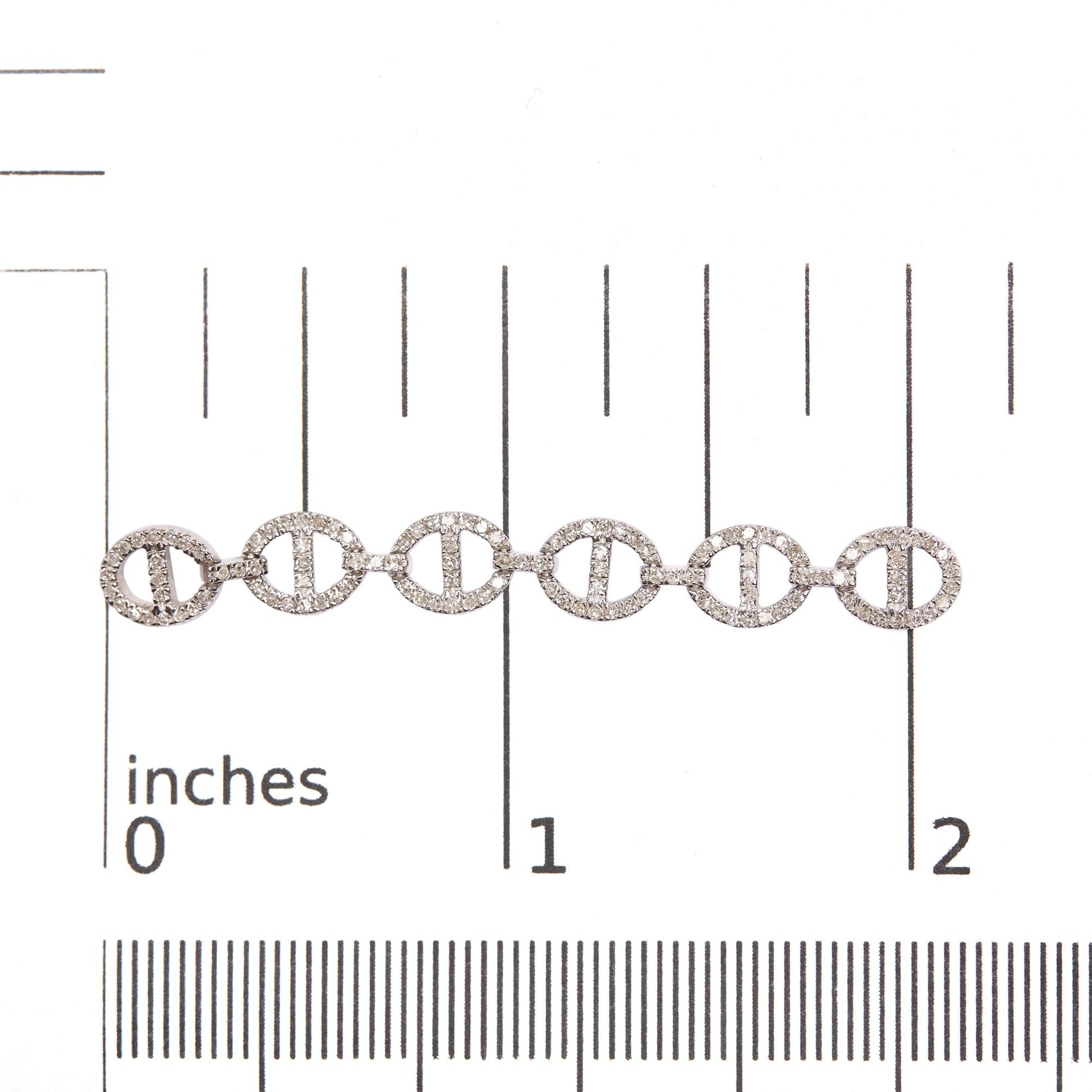Close-up front angle of white earrings placed on a scale, featuring several linked oval shapes encrusted with round white gemstones in prong settings.