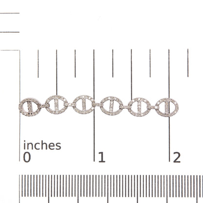 Close-up front angle of white earrings placed on a scale, featuring several linked oval shapes encrusted with round white gemstones in prong settings.
