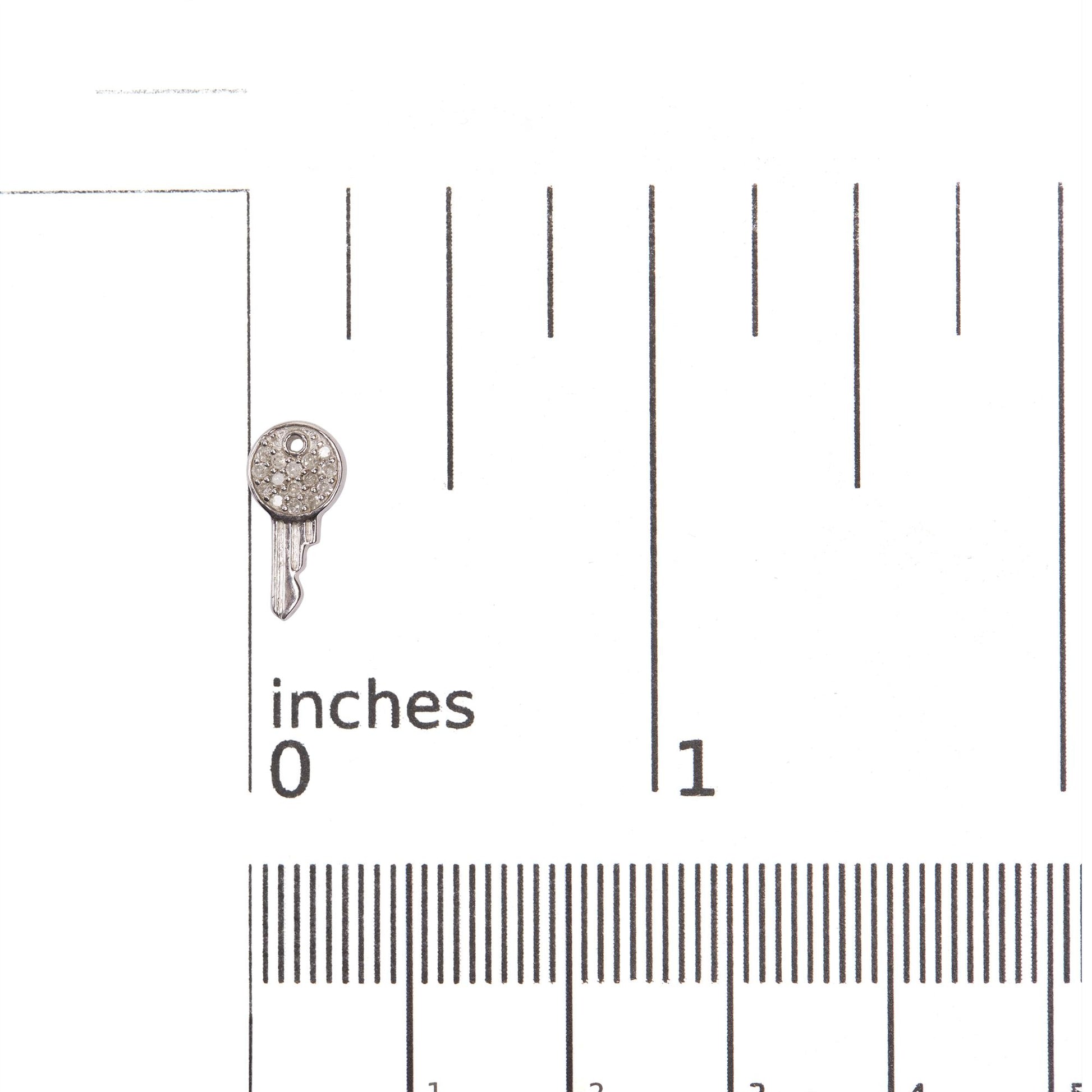 Close-up front view of one earring shown on a scale for size reference, featuring a round shape with multiple small white gemstones set in prong settings on white metal.