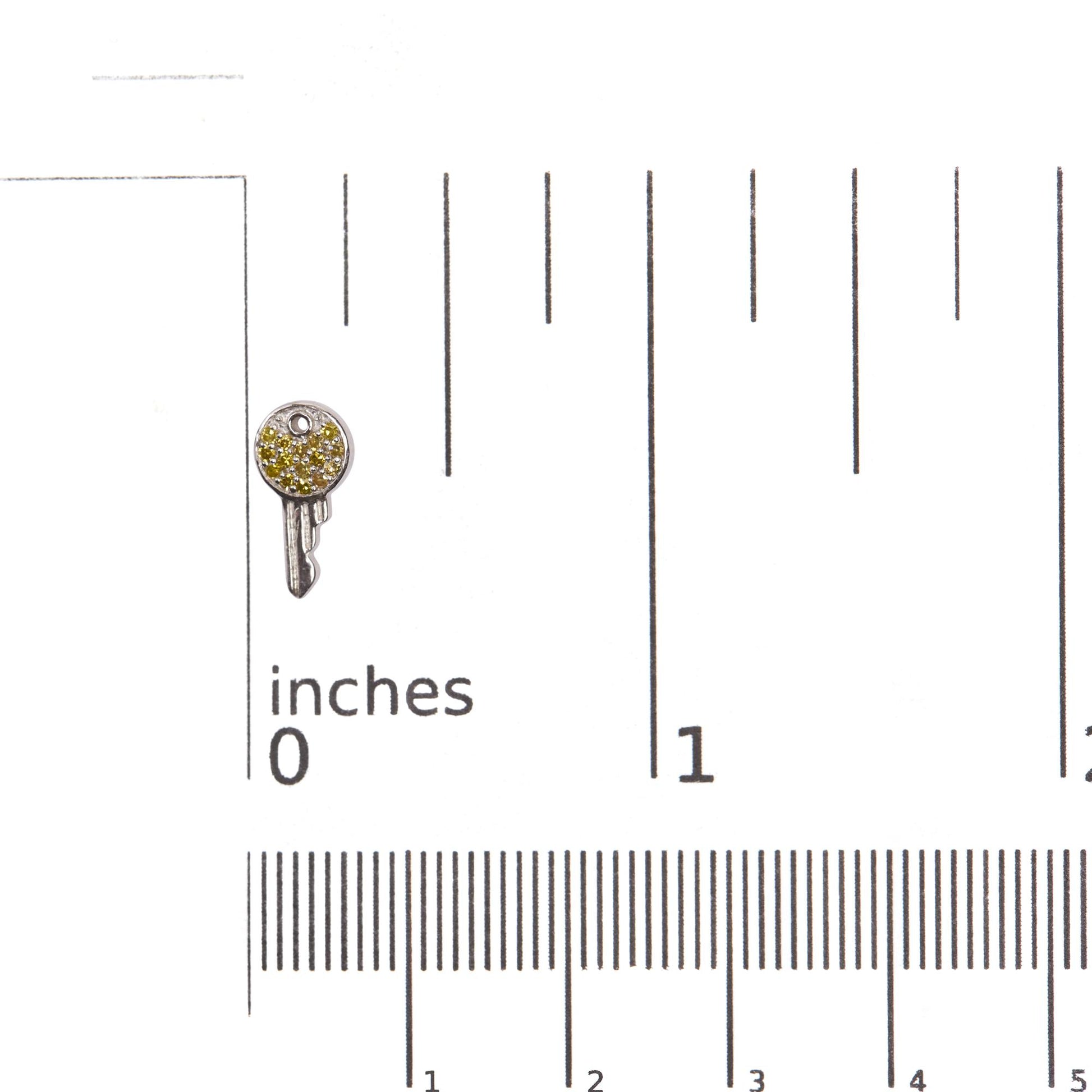 Close-up front angle of a white circular earring with prong-set round yellow gemstones, shown on a ruler scale.