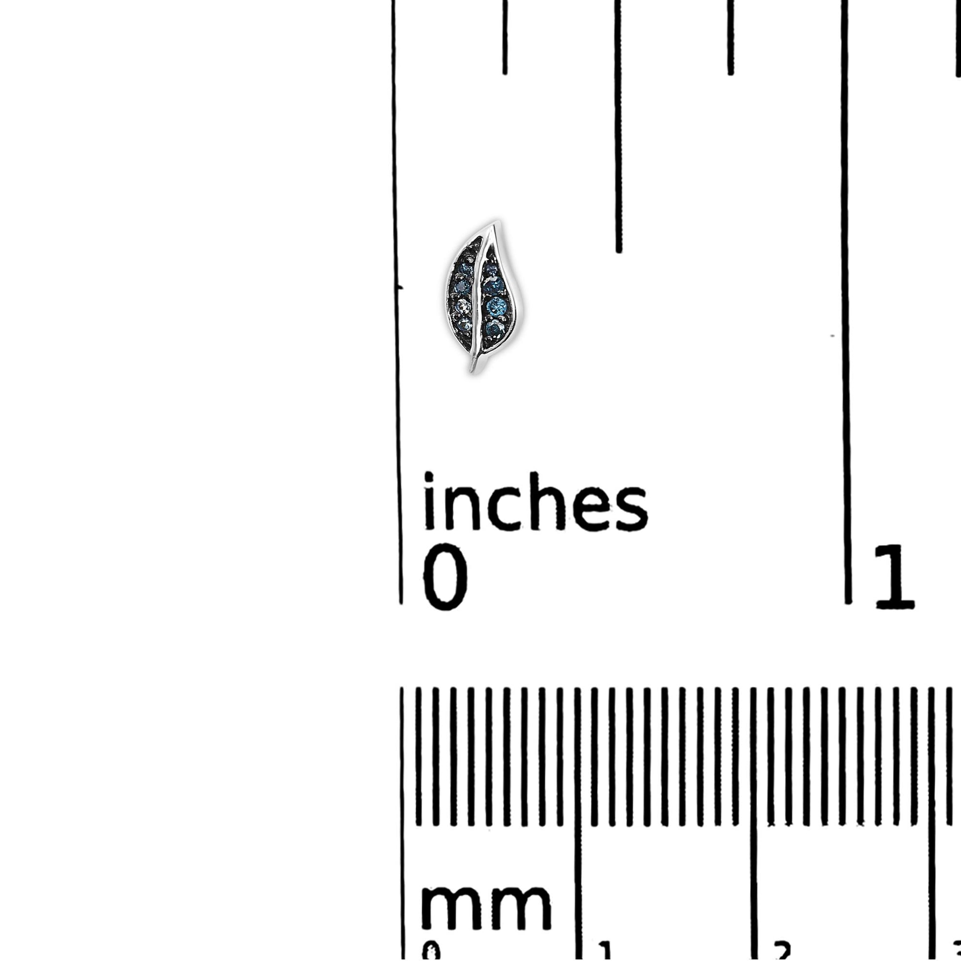 Earring shaped like a leaf with blue round gemstones set in prongs, shown on a scale with inch and millimeter markings, viewed from above.