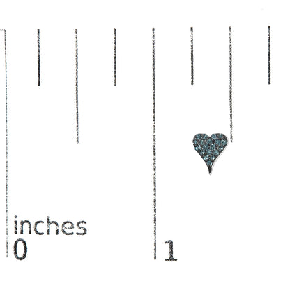 Close-up image of a white metal heart-shaped earring with round blue gemstones in prong setting, shown on a ruler for size reference.