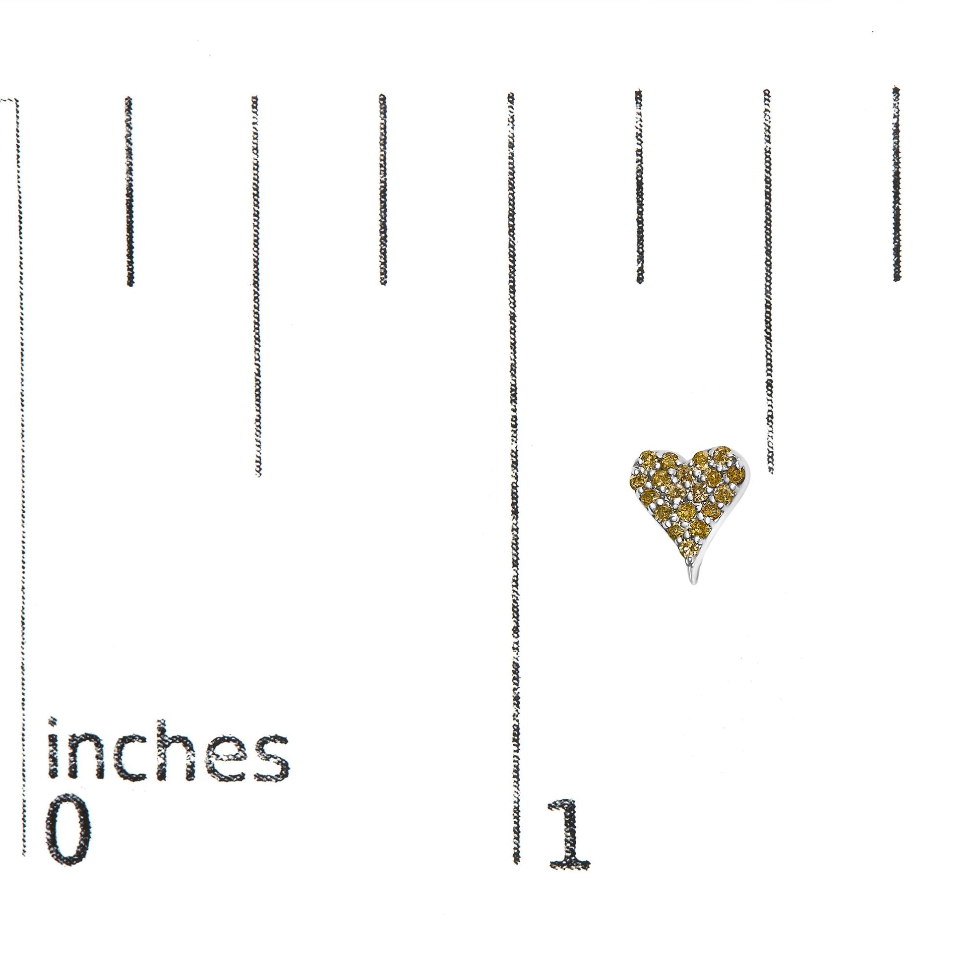 Close-up front view of a white metal heart-shaped earring adorned with round yellow gemstones in prong settings, placed on a ruler for size reference.