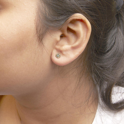 Close-up side view of a white metal stud earring with round yellow gemstones in a prong setting, worn on a model's ear.