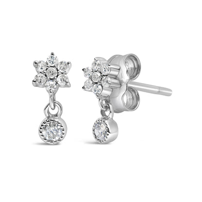 Front and side angled view of white metal stud earrings with round white gemstones in a floral cluster and a dangling round gemstone.