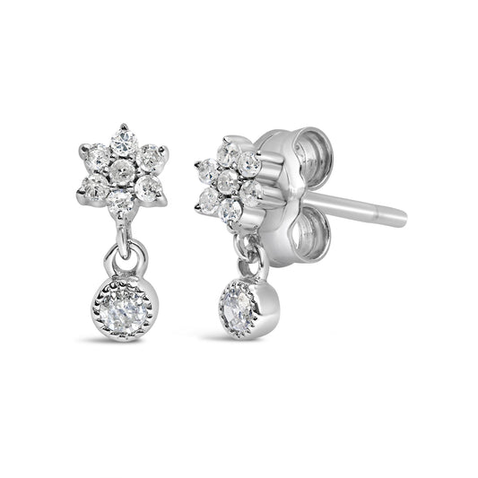 Front and side angled view of white metal stud earrings with round white gemstones in a floral cluster and a dangling round gemstone.