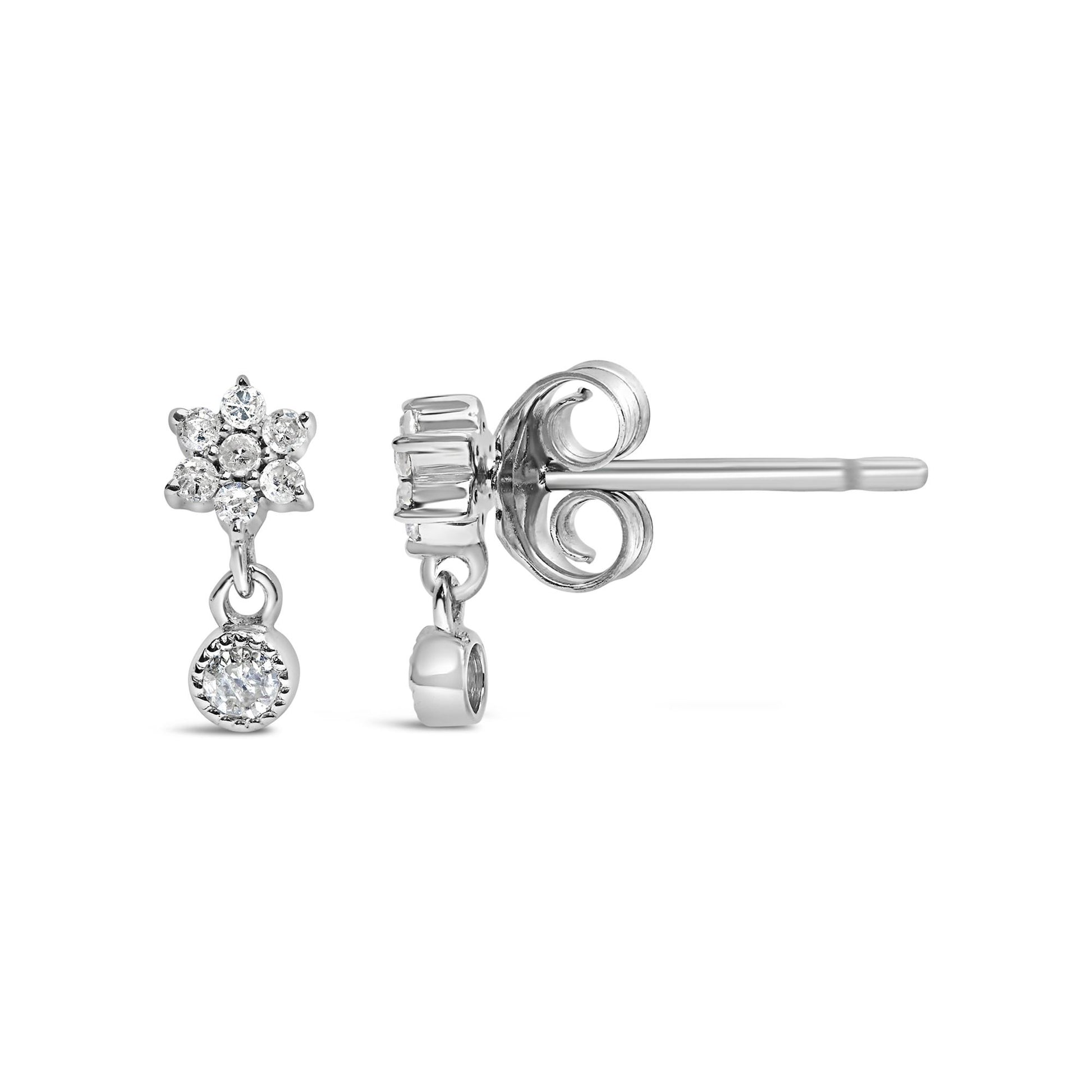 Front and side view of white metal stud earrings with cluster of round white gemstones in prong setting and a single round white gemstone drop, shown on a white background.