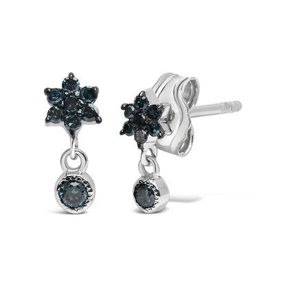 Pair of white metal earrings with blue round gemstones in prong setting arranged in a flower shape, each earring featuring a dangling round blue gemstone, shown in a close-up angled front and side view.