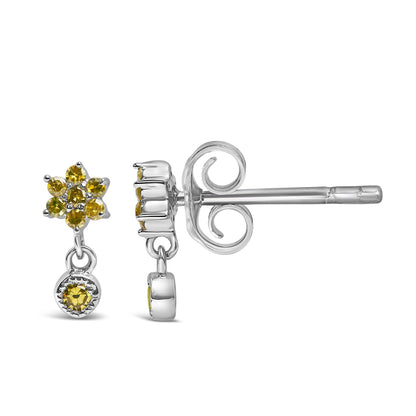 Close-up side angle of white metal earrings with round yellow gemstones in prong settings, featuring a flower-like cluster and a single dangling gemstone.