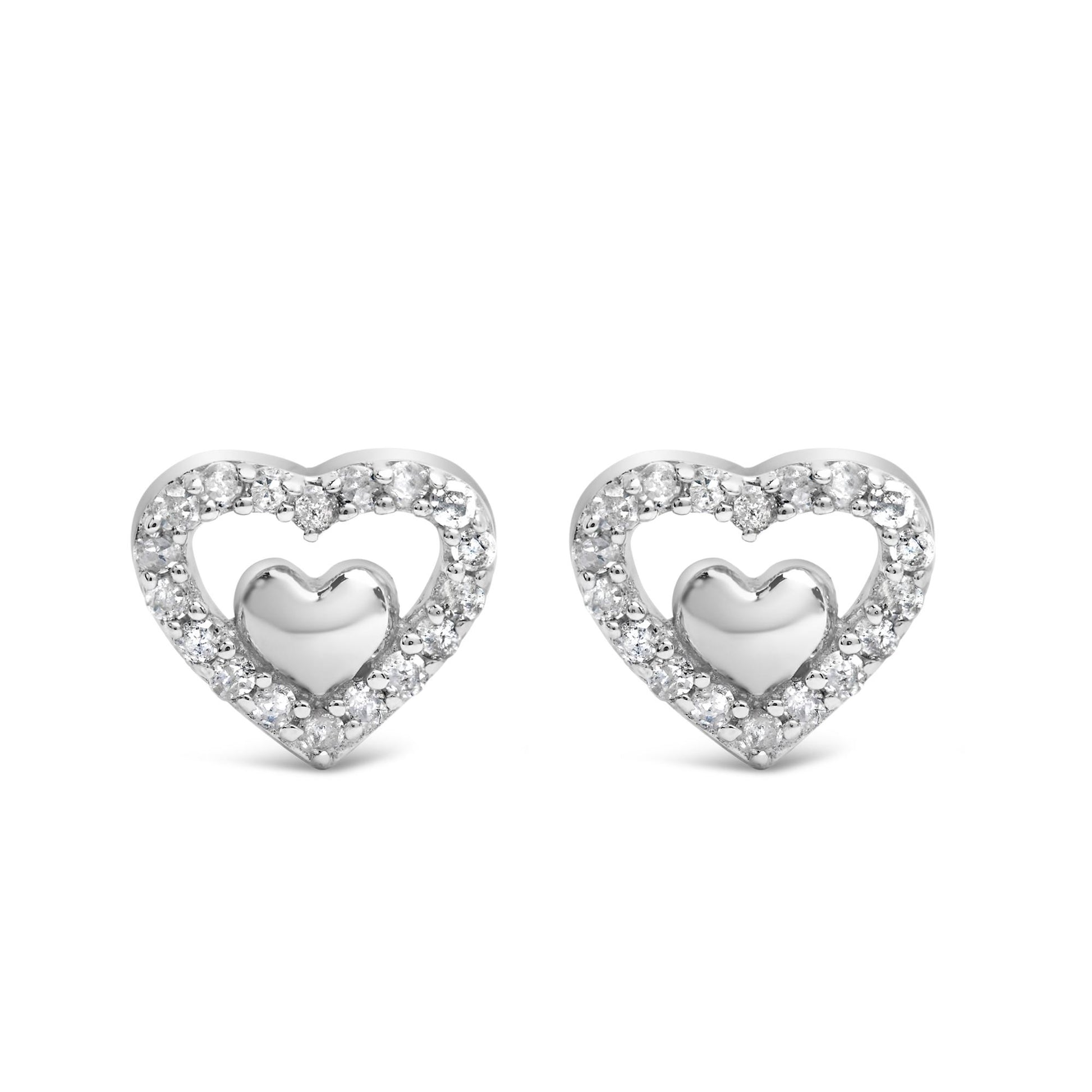 Front view of a pair of white metal heart-shaped earrings, each featuring a smaller solid heart in the center surrounded by an open heart outline set with multiple round white gemstones in prong settings.