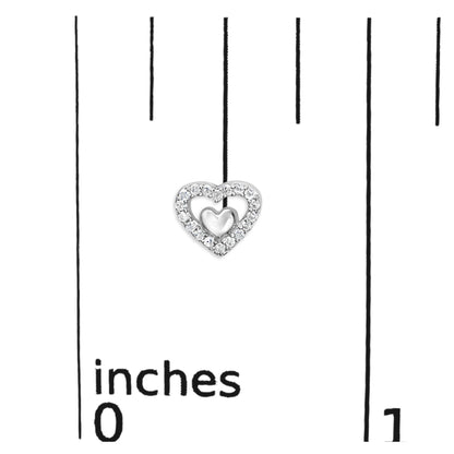 Close-up of a white metal heart-shaped earring with a smaller solid heart in the center, surrounded by round white gemstones in prong setting, placed on a ruler for size reference.