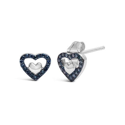 Close-up front and side angle of white metal heart-shaped earrings with inner solid heart and outer heart outlined with round blue gemstones in prong setting.