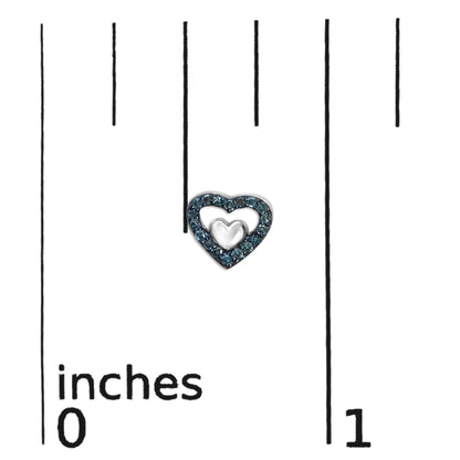 Close-up of a white heart-shaped earring with blue round prong-set gemstones, shown on a ruler for size reference.