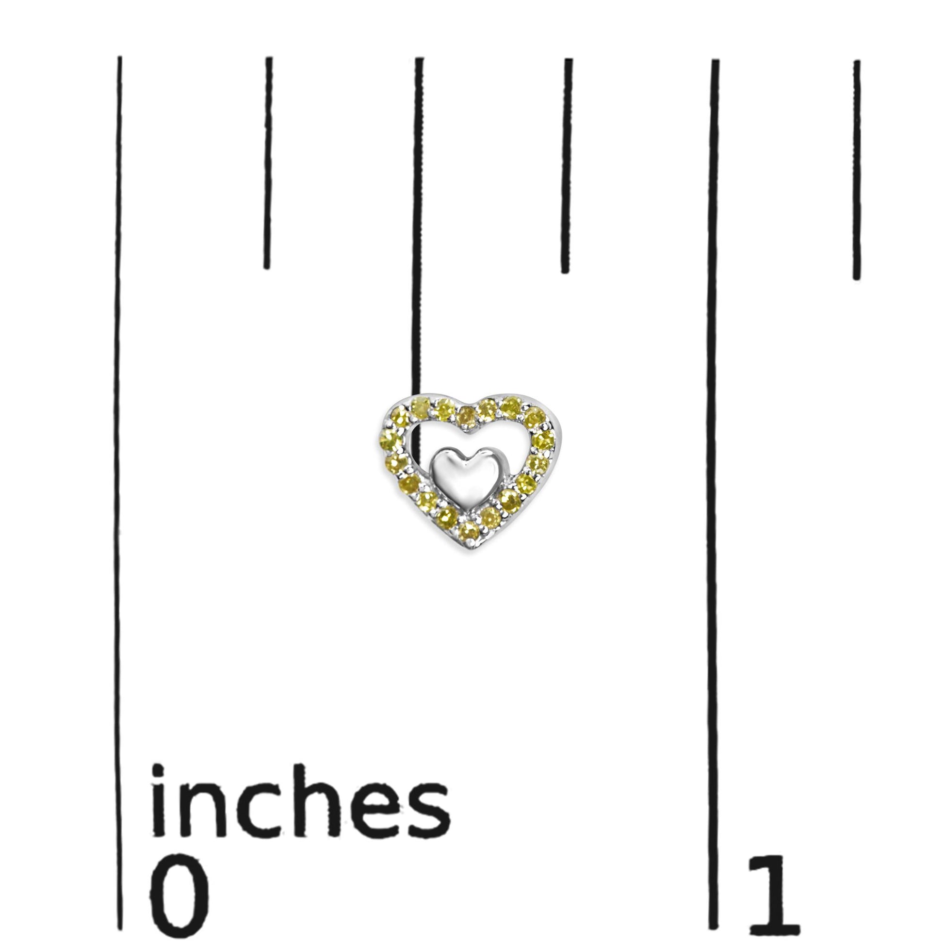 Close-up front view of a white metal heart-shaped earring with yellow round prong-set gemstones, displayed on a ruler for size reference.