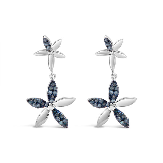 Front view of a pair of white metal earrings designed as two connected four-petal flowers, each petal partially adorned with small round blue gemstones in prong settings.