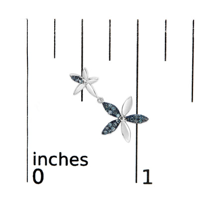 Close-up top view of a white metal dangle earring with two flower shapes, featuring round blue gemstones in a prong setting, shown on a scale.