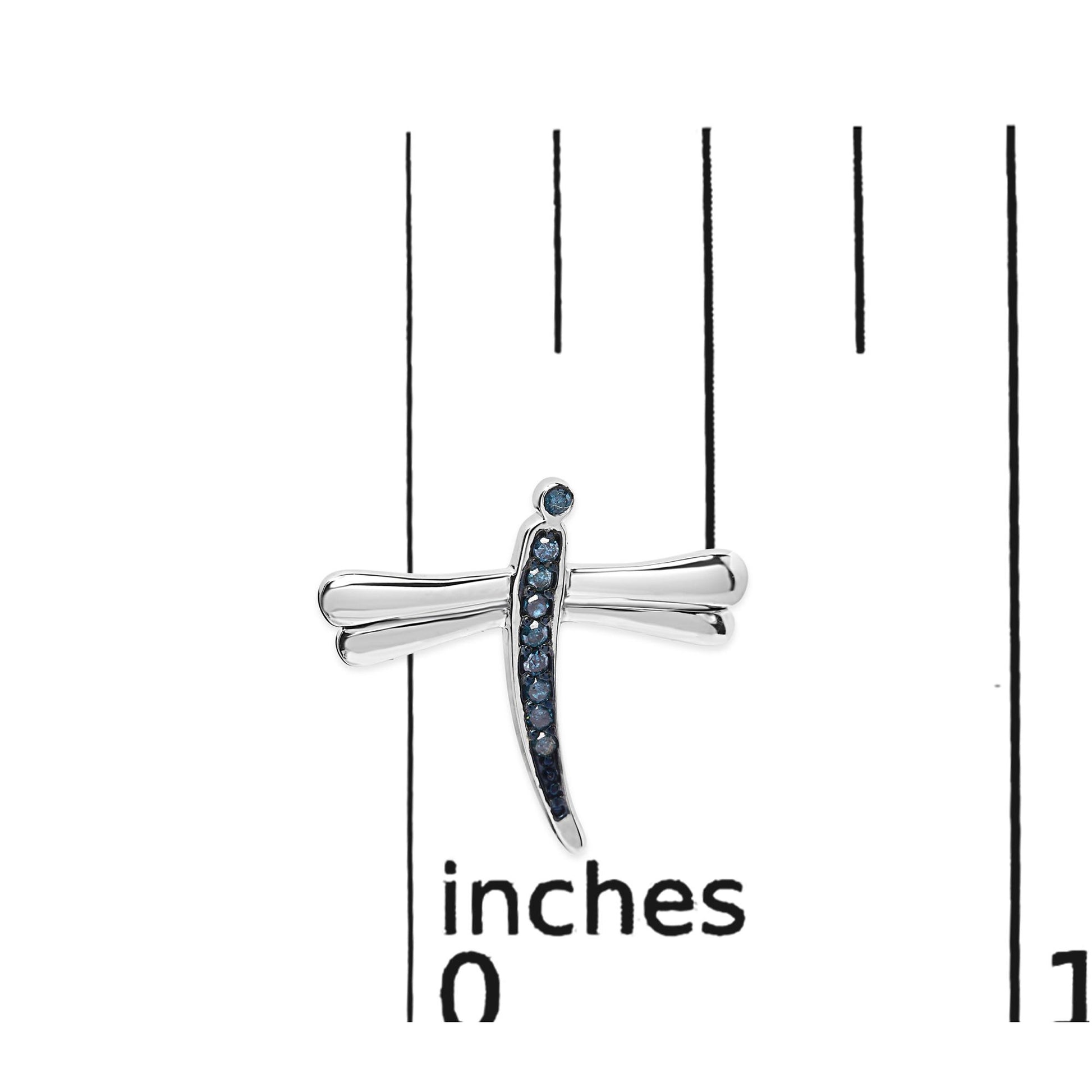 Close-up front view of white metal dragonfly-shaped earring with blue round prong-set gemstones, displayed on a ruler for size reference.