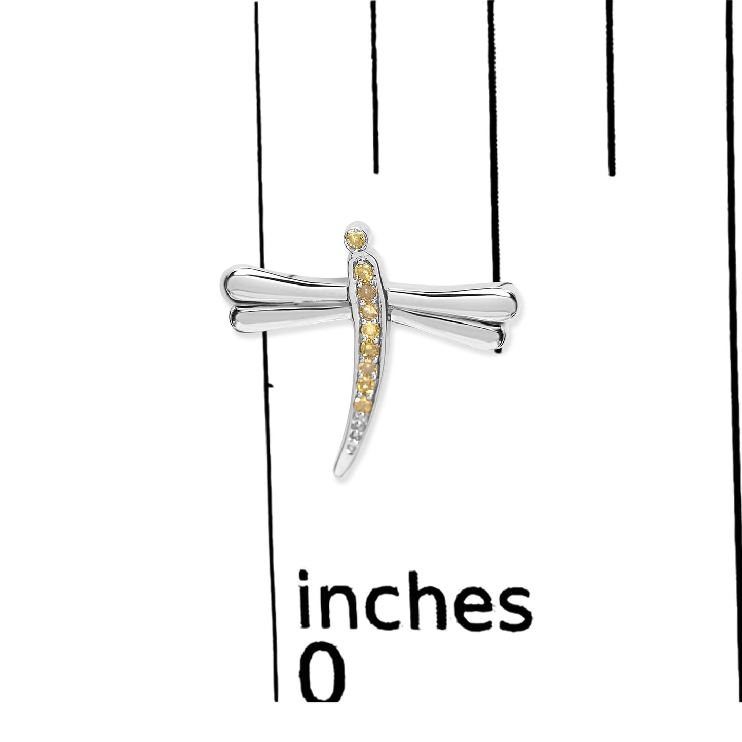 Close-up front view of a white metal dragonfly-shaped earring with prong-set round yellow gemstones, placed on a ruler for size reference.