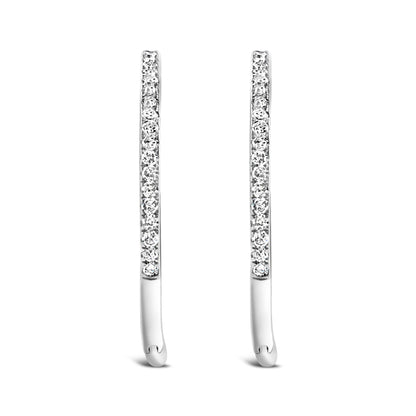 Front angled view of a pair of slim white metal earrings set with round white gemstones in prong settings.