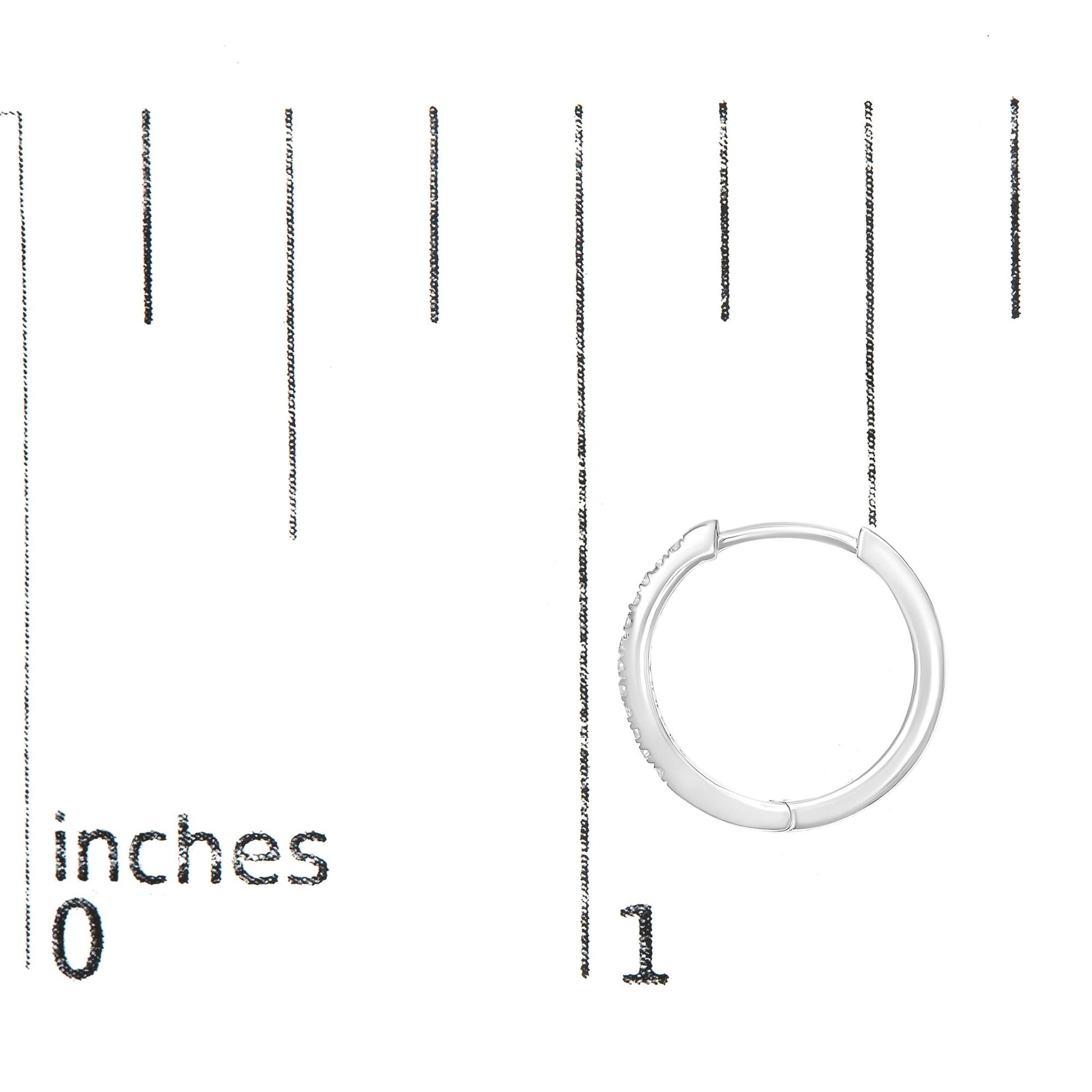 White metal hoop earring with round white gemstones set on the outer front side, shown on a ruler for size reference, front angle.