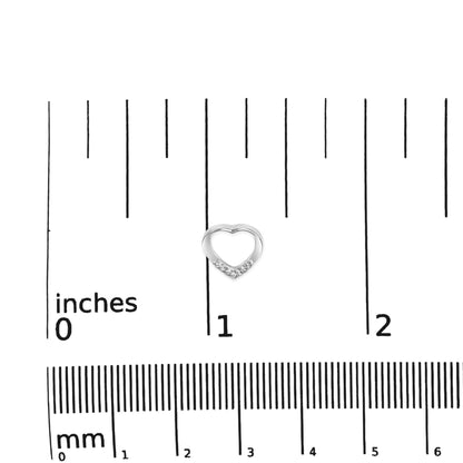 Close-up top view of a small white metal heart-shaped earring with round white gemstones set in a prong setting, placed on a ruler for size reference.