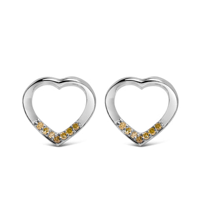 Front angle view of a pair of white heart-shaped earrings with round yellow gemstones set in prongs along the bottom inner edge.
