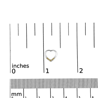 Close-up front view of a white heart-shaped earring with small yellow round gemstones along the lower curve, placed on a ruler for size reference.
