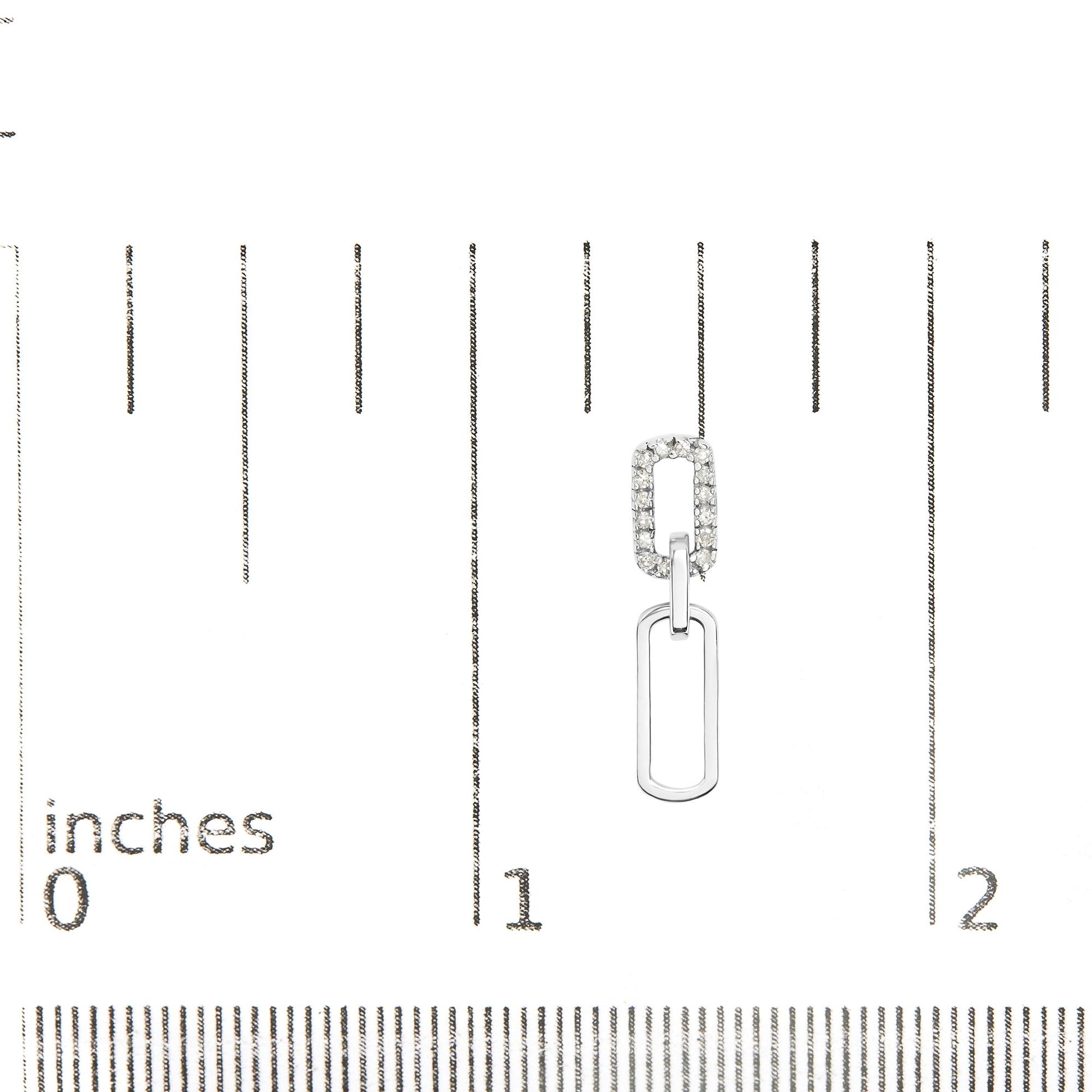 Close-up of white metal dangle earring with two linked geometric shapes, one encrusted with white gemstones, displayed on a ruler for size reference.