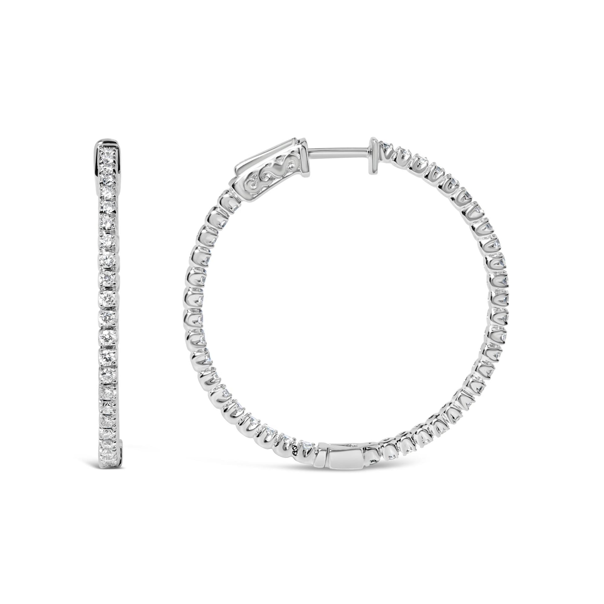 Pair of white metal hoop earrings with round white gemstones in prong setting, one shown from the side and the other from the front, on a white background.