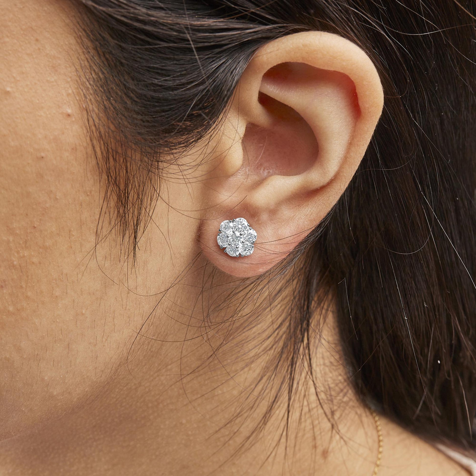 Close-up side angle of a white metal cluster earring with multiple round white gemstones in prong settings, worn on a model's ear.