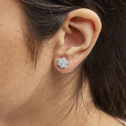 Close-up side angle of a white metal cluster earring with multiple round white gemstones in prong settings, worn on a model's ear.