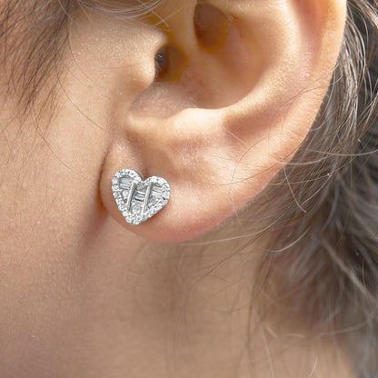 Close-up side angle of a white heart-shaped earring on a model's ear, featuring round and baguette-shaped white gemstones in prong and channel settings.