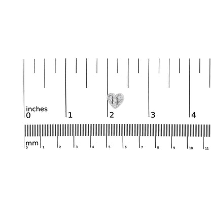 Close-up front view of small white metal heart-shaped earring with round and baguette white gemstones, placed on a ruler for size reference.