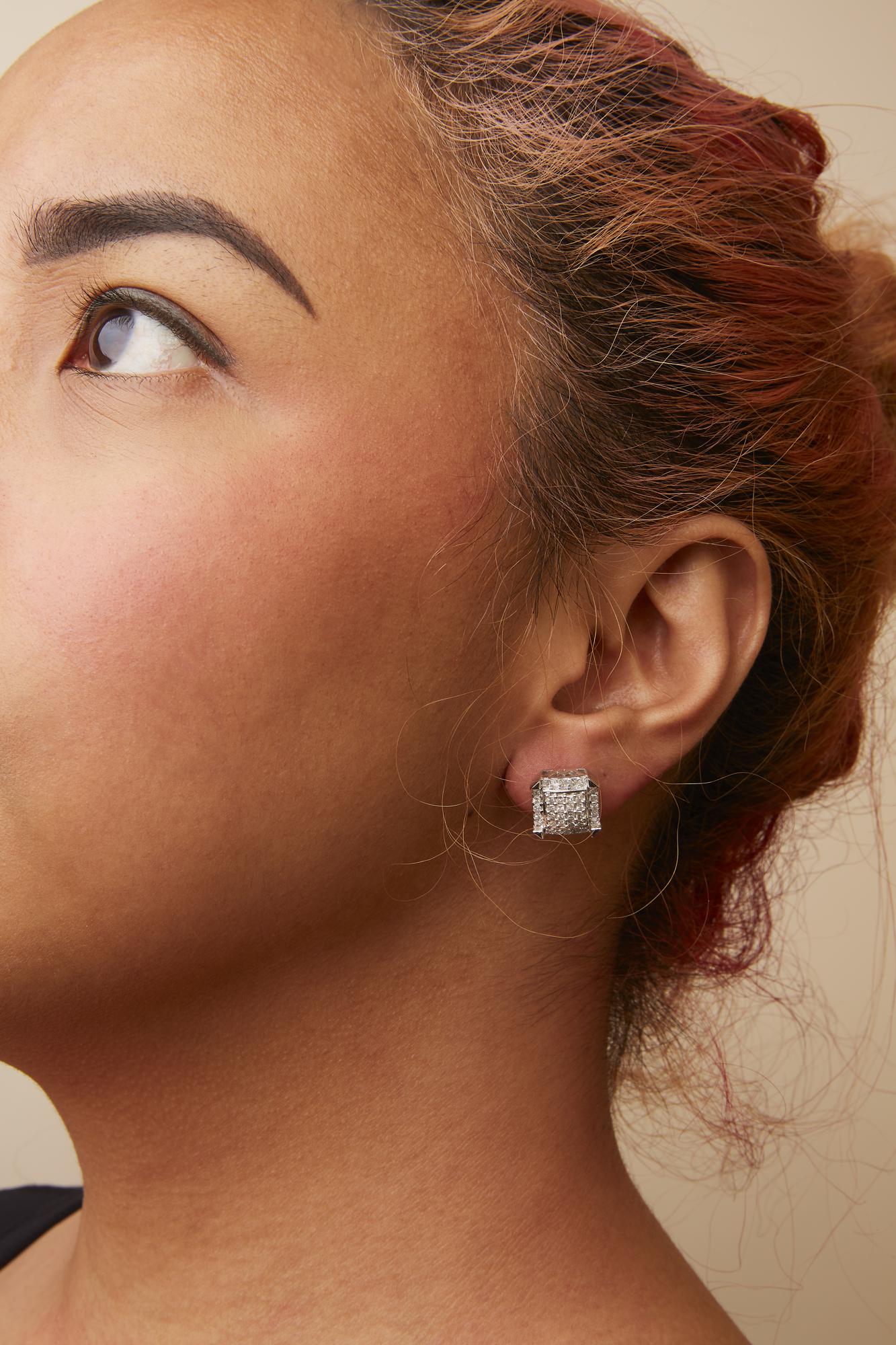 Close-up side view of a white metal stud earring with clustered princess-shaped white gemstones, worn on a model.