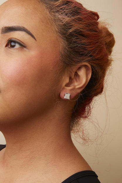 Close-up side angle of a model wearing white metal square stud earrings with multiple small white gemstones in prong settings.