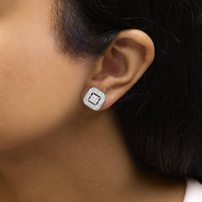Close-up side view of a white metal square-shaped earring on a model ear, featuring princess-shaped white gemstones in an invisible setting surrounded by round-shaped white gemstones in prong settings.
