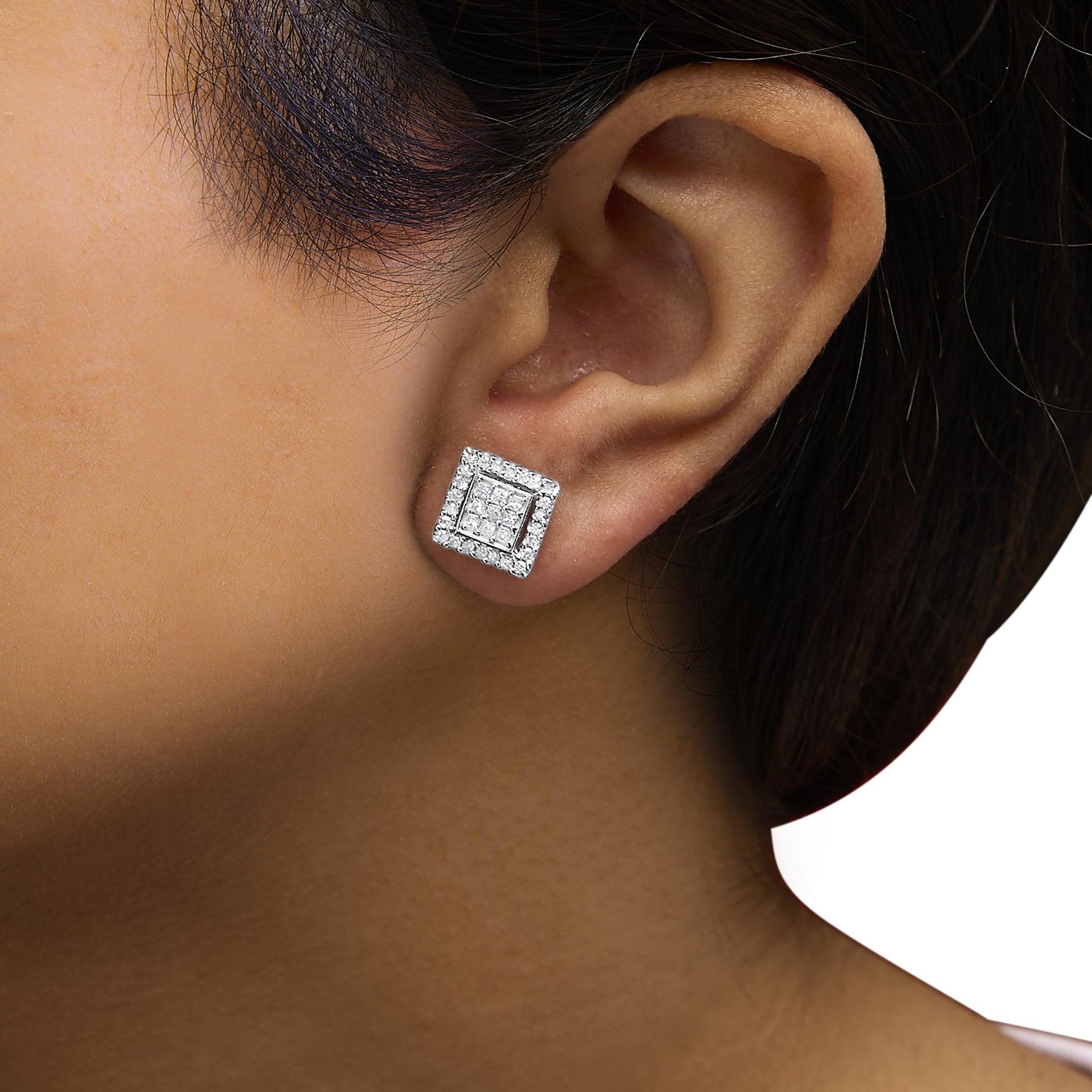 Close-up side view of a model wearing white metal square-shaped stud earrings with princess-shaped gemstones in an invisible setting at the center, surrounded by round-shaped gemstones in a prong setting.