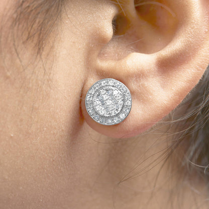 Close-up side view of a white metal circular earring on a model's ear, featuring round prong-set white gemstones around the edge and princess-shaped invisible-set white gemstones in the center.