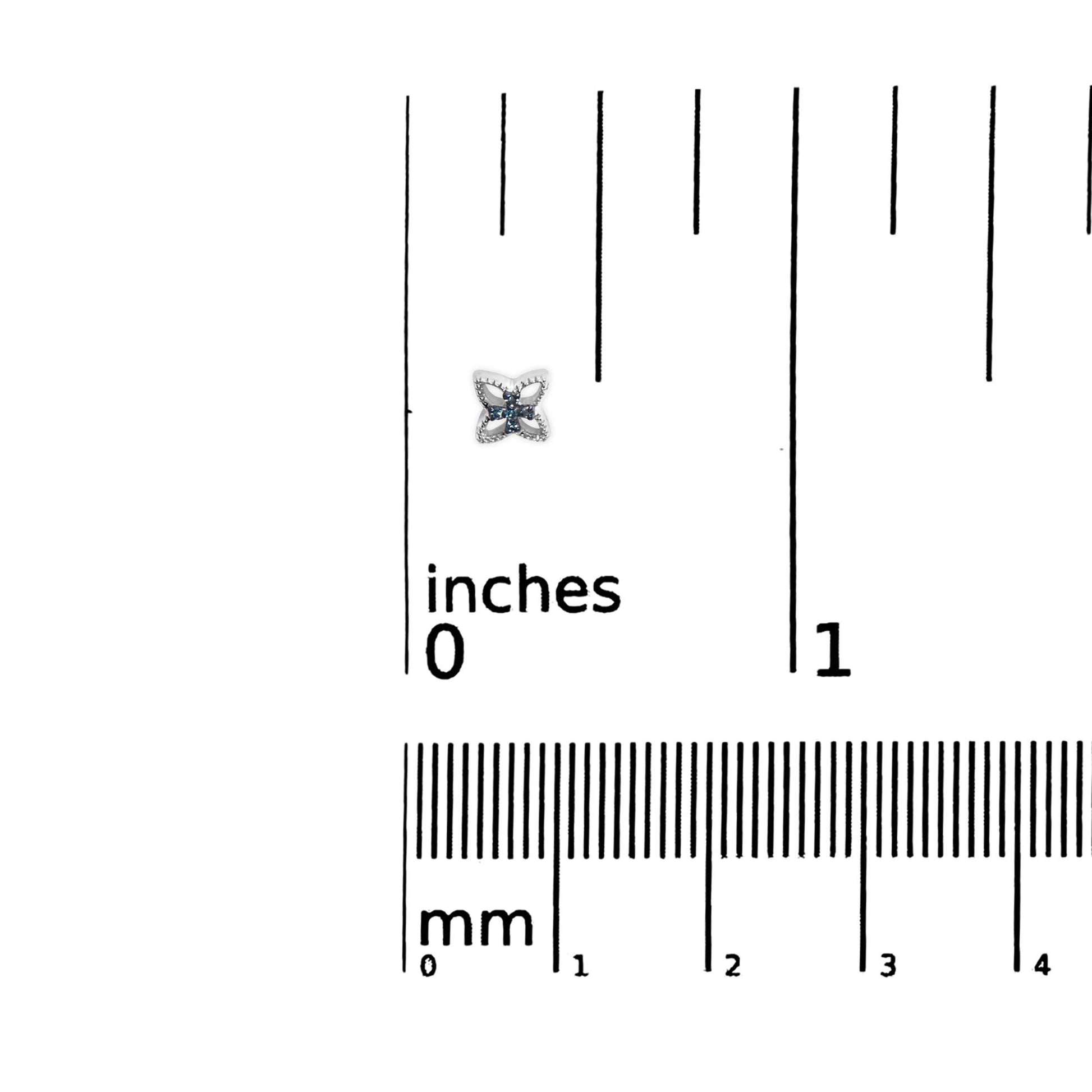 Close-up image of a white metal earring with a flower-like design featuring round blue gemstones in prong settings, placed on a ruler for size reference.