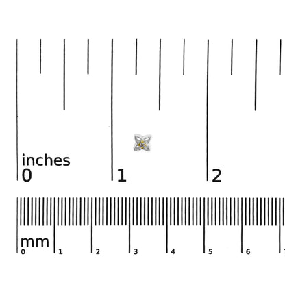 White metal earrings with a floral design featuring round yellow gemstones in prong settings, shown on a ruler for size reference, top-down angle.