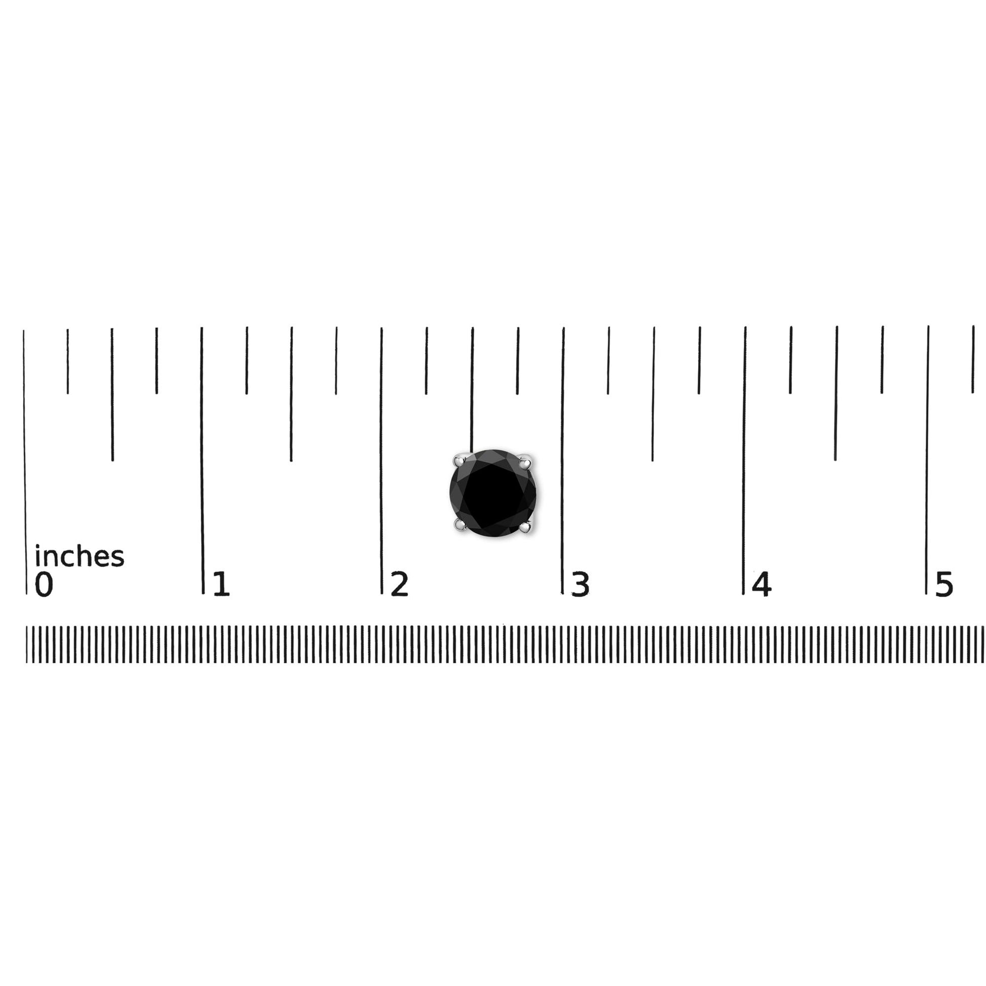 Close-up image of a single white metal earring with a round black gemstone in a four-prong setting, placed on a ruler for size reference.