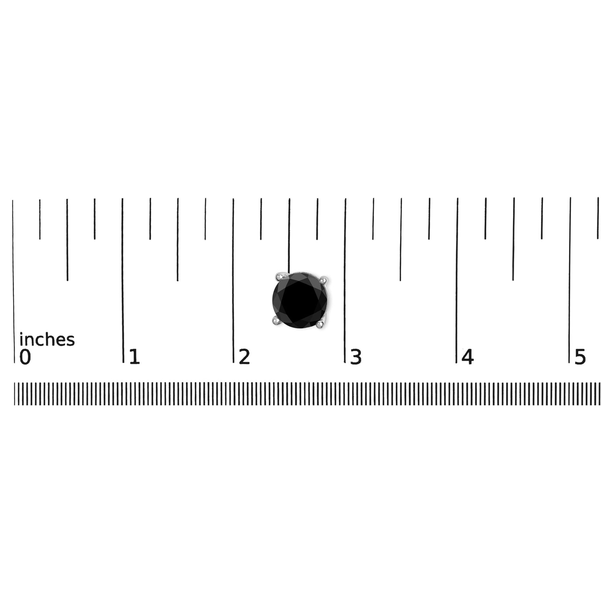 Close-up of a single white metal earring with a round black gemstone in a 4-prong setting, placed on a ruler for size reference, shot from above.