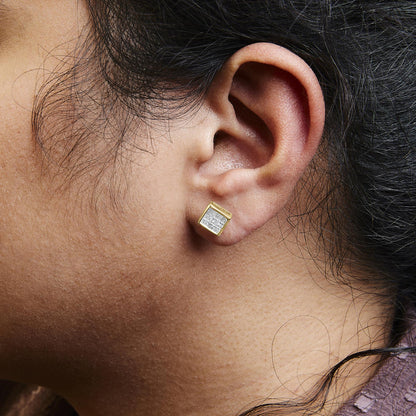 Close-up side view of a yellow metal square stud earring with multiple small white gemstones in an invisible setting, worn on a model's ear.