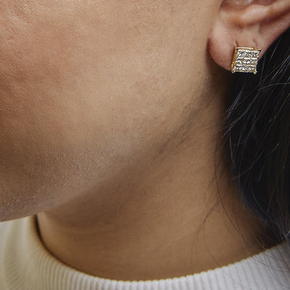 Close-up side view of a yellow metal square-shaped earring with white princess-shaped gemstones in an invisible setting, worn on a model.