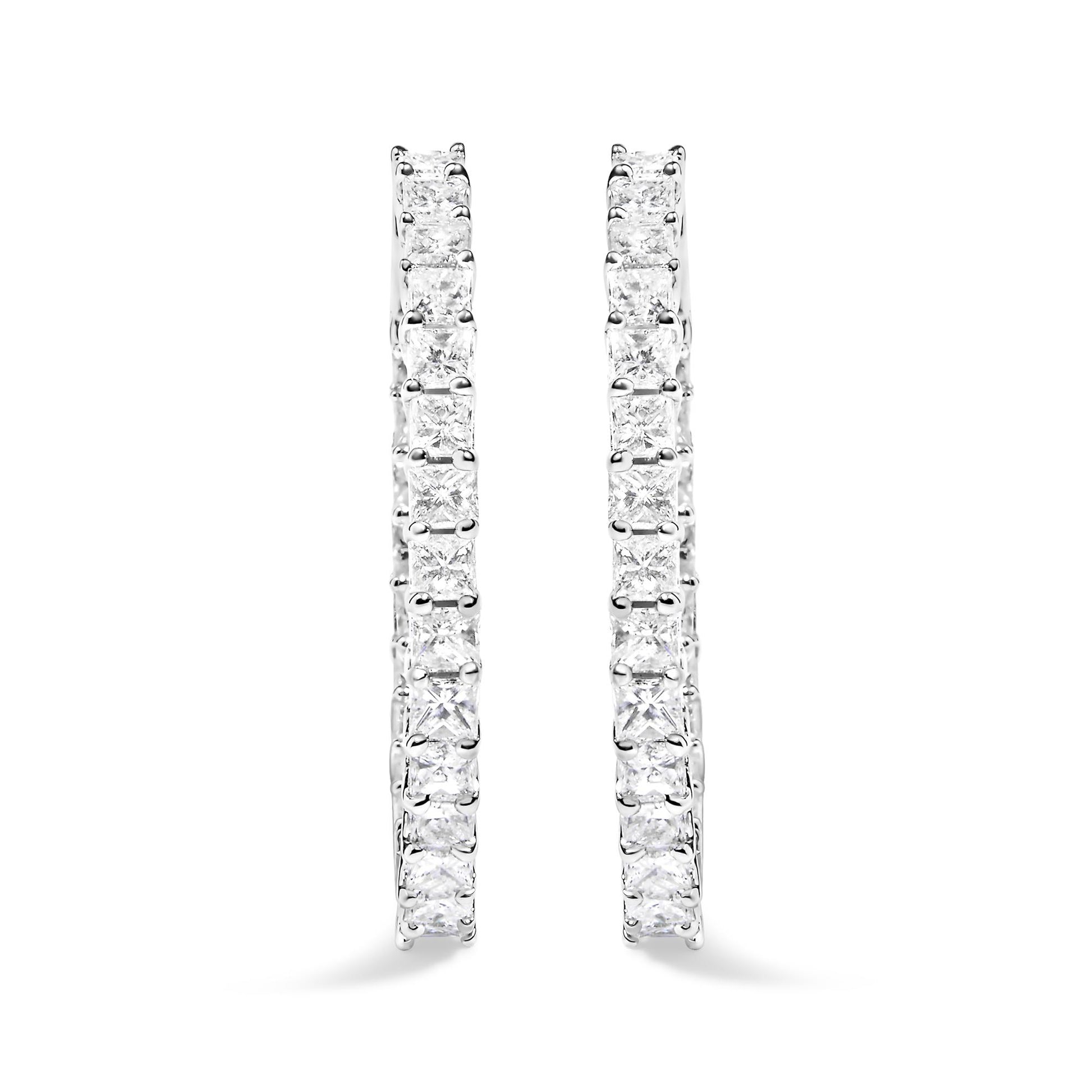 Close-up front view of white metal hoop earrings set with two rows of princess-shaped white gemstones in shared prong settings.