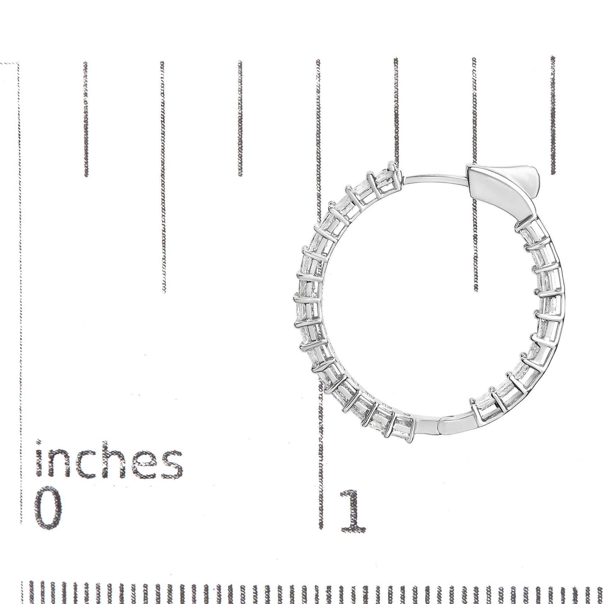 Close-up front angle of a white metal hoop earring with shared prong settings holding white princess shape gemstones, placed on a ruler for size reference.