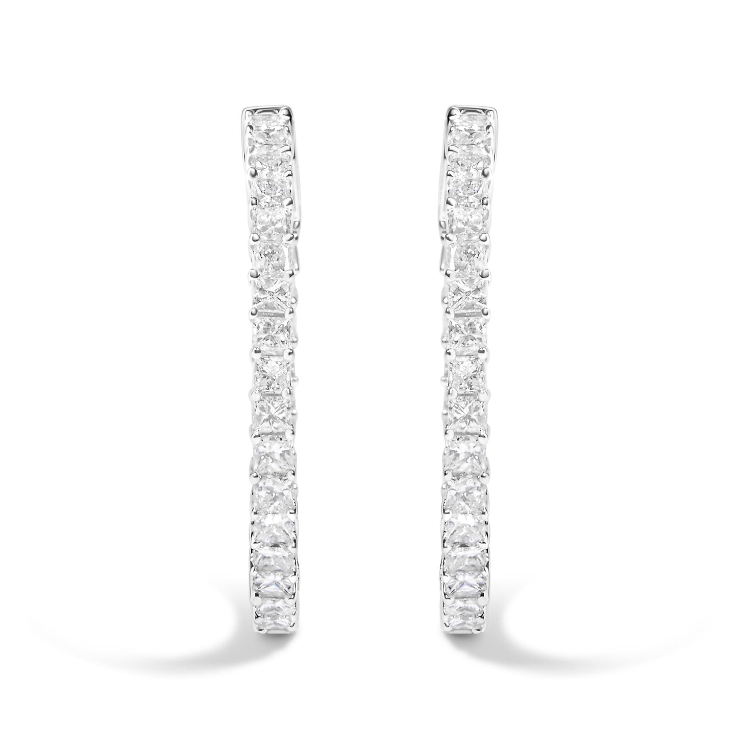 Front angle close-up of a pair of white metal hoop earrings set with square and round white gemstones in a shared prong setting.