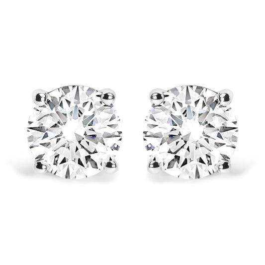 Front view of a pair of white metal stud earrings, each set with a round white gemstone in a four-prong setting.